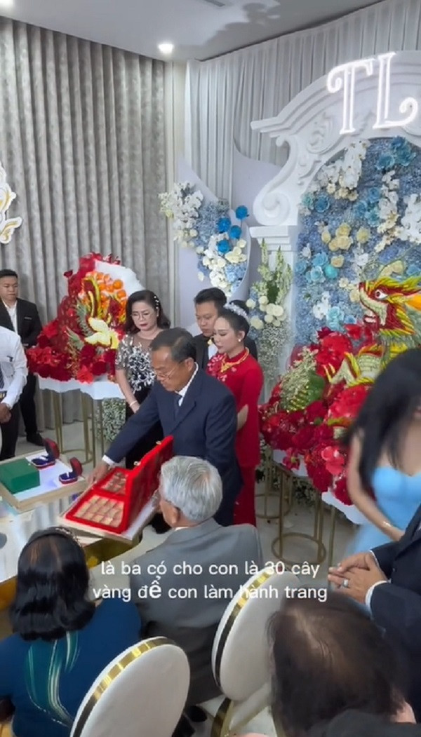 “Món quà đầu tiên là chiếc nhẫn hột xoàn 9 ly8, 1 cái vòng 8 ly 6 và một cái đồng hồ rolex dành cho chú rể. Tiếp theo đây là ba có cho con 30 cây vàng để con làm hành trang là món quà thứ 2. Món quà thứ 3 nữa là ba có cho con 30 mảnh đất tại tỉnh Bình Phước. Đây ba với mẹ đã ký tặng qua cho con, tất cả đều là tên con hết...
