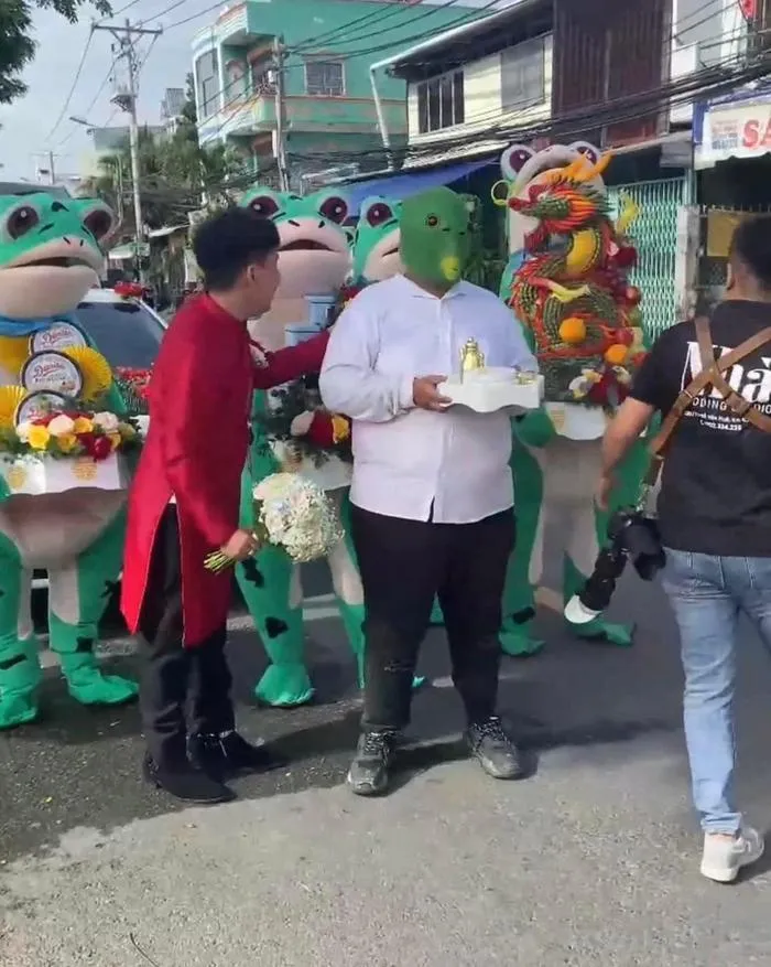 Thậm chí, người dẫn đoàn bê tráp còn đội mặt nạ khá kỳ dị. Chỉ riêng chú rể vẫn giữ được sự nghiêm túc khi diện áo dài, tay cầm hoa trang trọng.