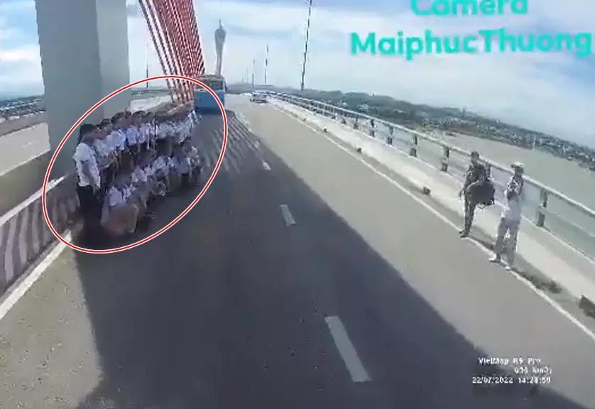 Trước đó, xuất hiện đoạn clip tài xế điều khiển xe tải đúng làn đường phải thắng gấp khi thấy nhóm hơn 20 người lớn mặc đồng phục hồn nhiên đứng dàn hàng chụp ảnh trên cầu Cửa Hội.