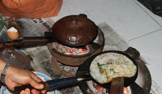 Bánh xèo đổ trên bếp than hồng nóng hổi, đổ tới đâu ăn tới đó, cuốn bánh tráng kèm các loại rau sống, chấm mắm pha tỏi ớt, ngon khó cưỡng.