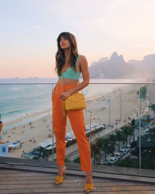 Rocky Barnes Rocky Barnes ''chơi trội'' với lối chơi màu độc đáo khi ghép cặp crop top màu xanh với quần cạp cao phủ sắc cam và sandals, túi xách đều có tông vàng rực rỡ.