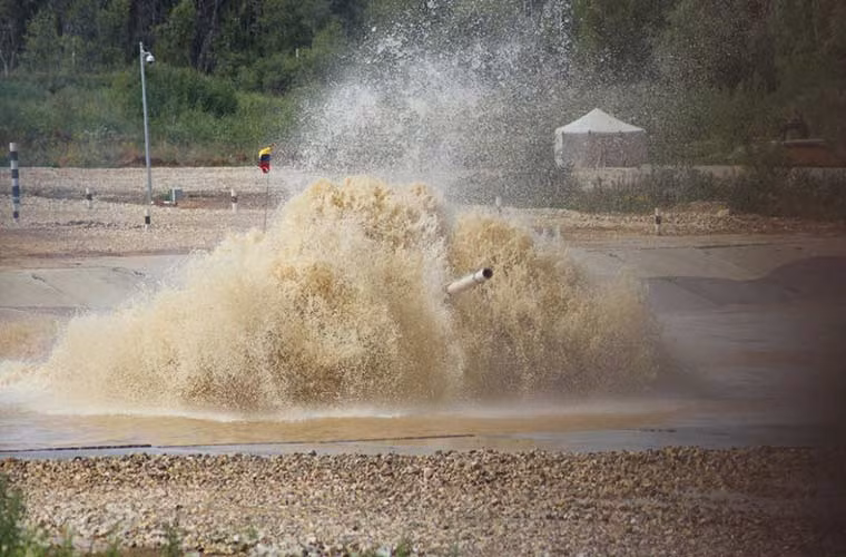 Trong khi đó, các xe tăng T-72B3 do các đội Venezuela, Armenia, Kuwait điều khiển nhiều lần gặp nạn trong các phần thi do sự nóng vội, kĩ năng điều khiển kém. Ảnh: xe tăng T-72B3 của Venezuela lội nước với tốc độ cao dẫn đến nước trùm cả lên xe tăng, sau đó chiếc tăng đã chết máy và buộc phải dùng xe cứu kéo.