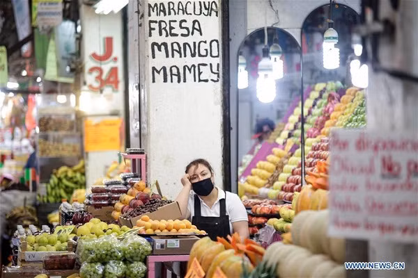 Người phụ nữ đeo khẩu trang ngồi bán hàng trong một khu chợ thực phẩm ở Mexico City ngày 18/6.