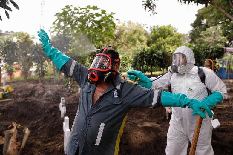 Nhân viên tang lễ được phun khử trùng sau lễ tang của một phụ nữ tử vong vì virus corona tại nghĩa trang Santa Tecla hôm 24/6.