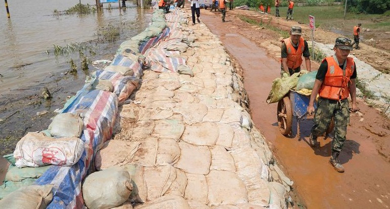 Các sĩ quan vận chuyển những bao cát để đắp bờ kè ngăn lũ ở Poyang, tỉnh Giang Tây, ngày 15/7.