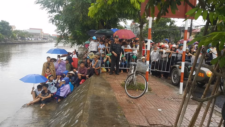 Mặc dù trời đang mưa nặng hạt nhưng với tình cảm dành cho Chủ tịch nước, người dân vẫn đứng đợi. Ảnh Hải Ninh