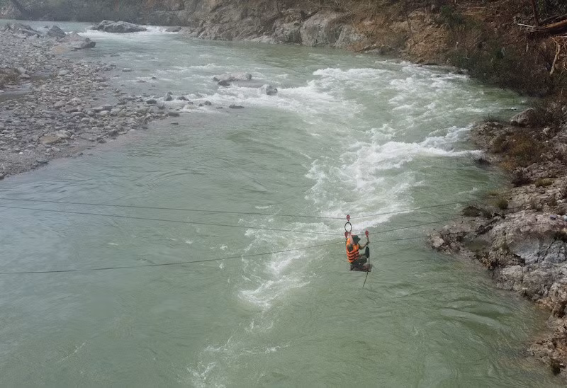 Mưa lũ kéo dài, nước sông Leng dâng cao, cán bộ, chiến sĩ phải dùng ròng rọc đưa người sang bên kia sông (nơi có điểm bồi lấp) tiếp tục tìm kiếm. Ảnh: THANH NHẬT