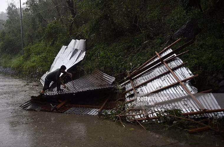 Người đàn ông cố gắng vớt vát mái nhà bị thổi bay giữa lúc trời mưa bão.