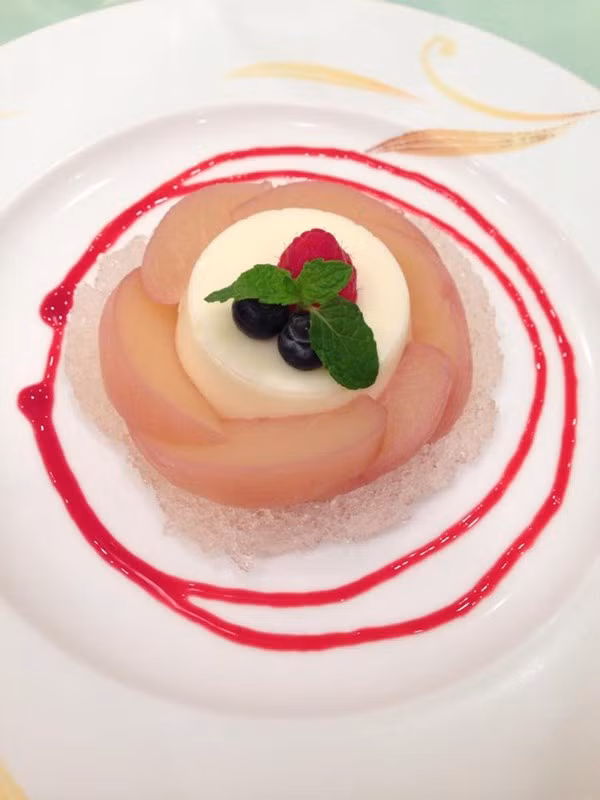 Đây là Panna cotta, món tráng miệng trình bày theo phong cách Nhật. Panna cotta được đặt bên trên một lớp đá bào, xung quanh là những lát đào được xếp khéo léo. Siro dâu tây cùng quả mâm xôi, việt quất và lá bạc hà được sắp xếp hài hoà, vừa tăng thêm hương vị vừa khiến món tráng miệng Nhật Bản này trở nên đẹp mắt. 
