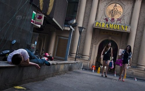 Lâu dần, con đường này trở thành nơi yêu thích của những người trẻ tuổi của thành phố ưa chuộng phong cách tiệc tùng, sàn nhảy hay con gọi là “phong cách club”. Trong ảnh, một người đàn ông say rượu nằm trên lan can bị hai cô gái làng chơi cười nhạo.