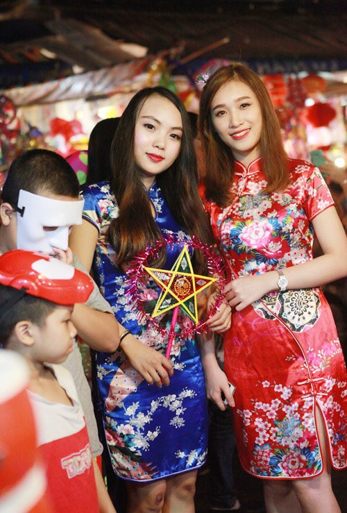 Hai bạn gái mặc sườn xám chụp hình trên phố.