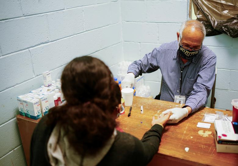 Bác sĩ xét nghiệm COVID-19 cho một phụ nữ tại trung tâm ở Ciudad Juarez hôm 7/4. Người phụ nữ này đã bị trục xuất khỏi Mỹ về Mexico cùng với con trai.