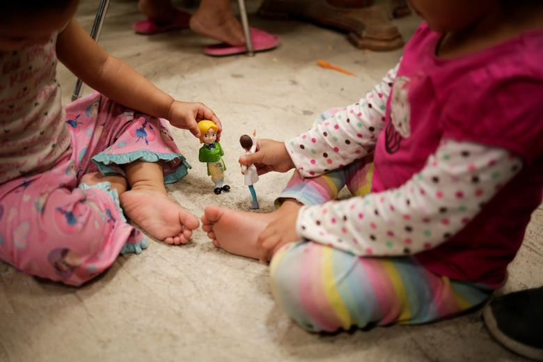 Hai bé gái di cư đến từ Trung Mỹ chơi búp bê trong trung tâm El Buen Samaritano ngày 21/3.