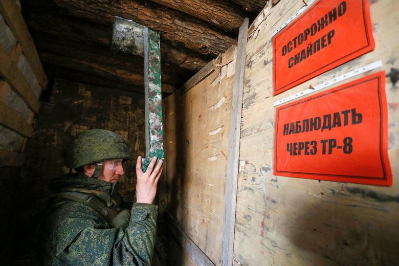 Thành viên của lực lượng vũ trang Cộng hòa Nhân dân tự xưng Donetsk sử dụng thiết bị để quan sát tại vị trí chiến đấu ở phía nam thành phố Donetsk, ngày 2/4. Tấm biển ở trên có nội dung: "Coi chừng. Bắn tỉa".