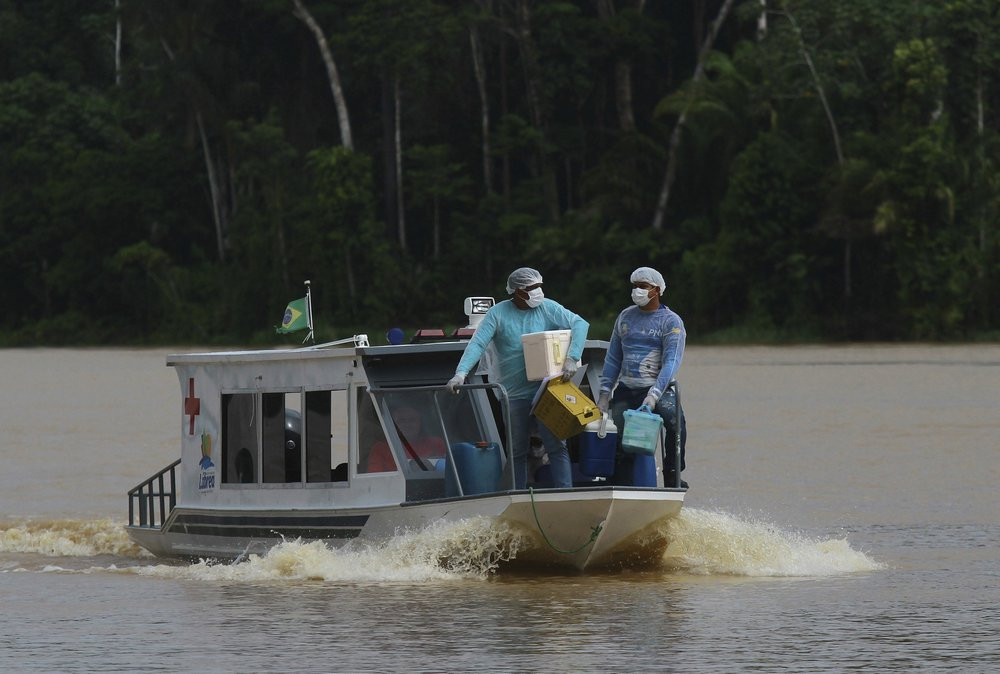 Nhân viên y tế Diego Feitosa Ferreira (phải), 28 tuổi, và Clemilton Lopes de Oliveira, 41 tuổi, đi trên thuyền đến cộng đồng Santa Rosa, bang Amazonas, Brazil, ngày 12/2/2021, để tiêm vắc xin COVID-19 của AstraZeneca cho người dân địa phương.