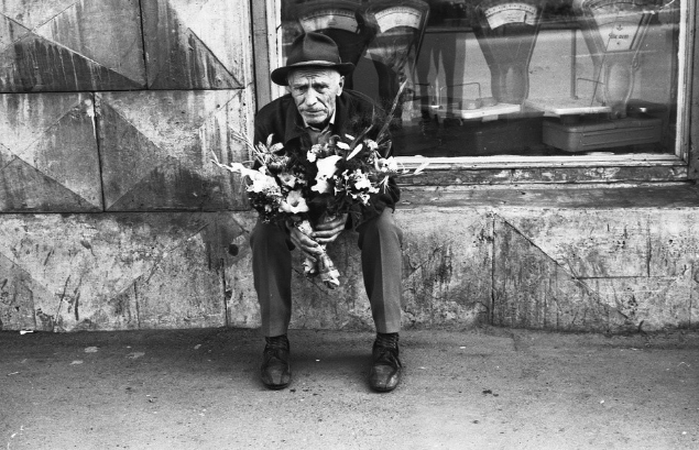 Người đàn ông lớn tuổi ngồi bán hoa ven đường.