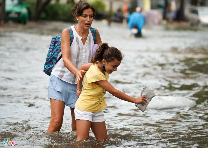 Người phụ nữ ngoại quốc cùng bé gái bước qua đoạn ngập.