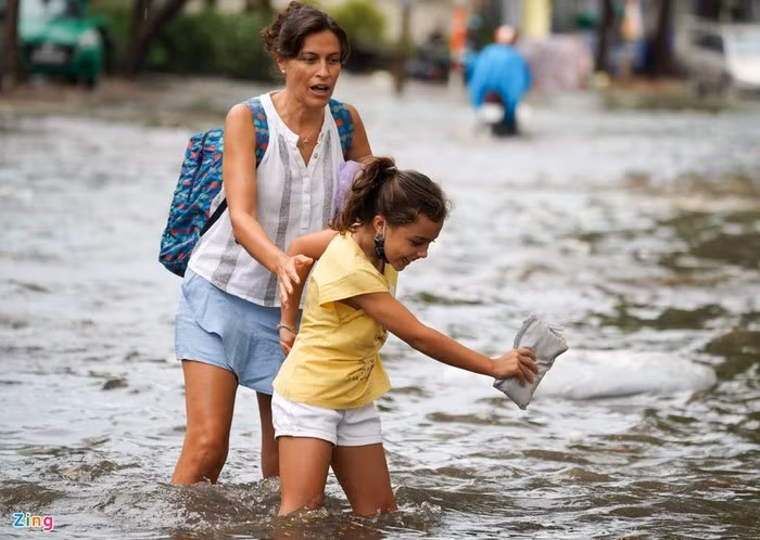 Người phụ nữ ngoại quốc cùng bé gái bước qua đoạn ngập.