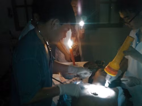 Các bác sĩ tại đảo Bạch Long Vỹ đang dùng đèn pin và điện thoại làm nguồn sáng để tiến hành phẫu thuật cho bệnh nhân. Ảnh: BS Nguyễn Đức Quân.