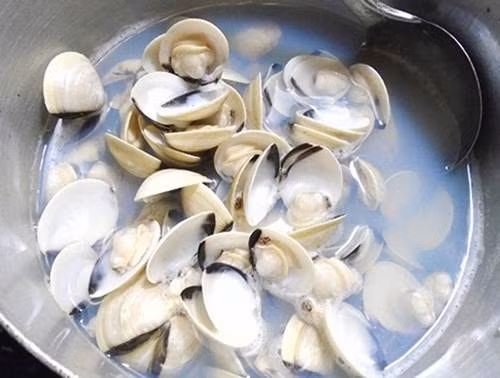 Bước 2: Ngao rửa sạch, cho vào nồi, đổ ngập nước rồi thêm vài hạt muối vào luộc. Khi ngao mở miệng thì bạn tắt bếp, vớt ra tách lấy phần thịt, ướp cùng mắm, mỳ chính, bột canh, 1/3 chỗ hành khô cho ngấm gia vị. Nước luộc ngao đổ ra bát cho lắng cặn.