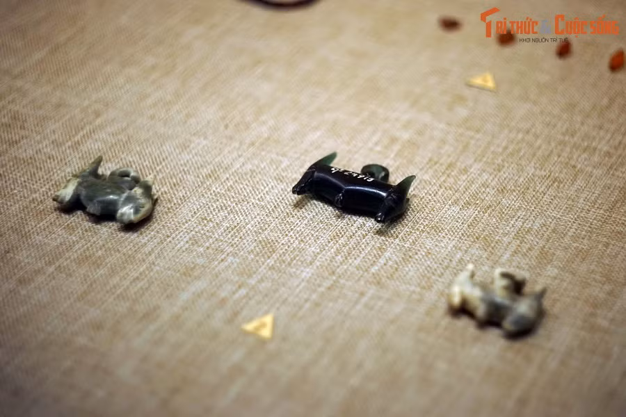 Hiện vật thủy tinh gồm khuyên tai hai đầu thú màu xanh nước biển và màu xanh rêu, khuyên tai ba mấu, khuyên tai hình khối 8 có màu xanh đen, khuyên tai hình vành khăn có màu xanh nước biển, hạt chuỗi có hình cầu màu xanh nước biển, vòng tay… Ảnh: Khuyên tai hai đầu thú bằng thủy tinh và đá ở Giồng Cá Vồ.