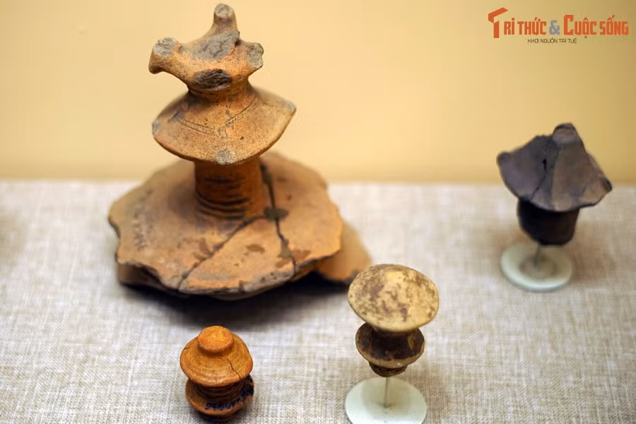 Mô hình tháp bốn mái trên đỉnh có gắn tượng hình chim, các trụ gốm hình con tiện, chân đế choãi trang trí văn khắc vạch, tượng hình chim… cũng phát lộ với số lượng lớn, cho thấy đây là biểu tượng có ý nghĩa quan trọng đối với dân cư Giồng Cá Vồ. Ảnh: Núm trang trí hình tháp trên nắp đồ đựng Giồng Cá Vồ.