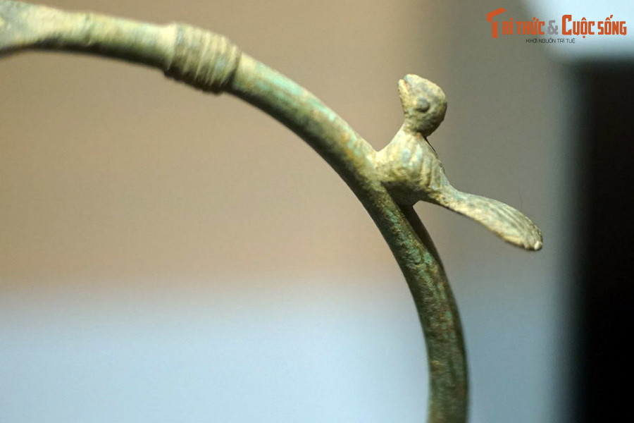 Hình một loài chim nhỏ có đuôi dài trên quai của chiếc đèn treo bằng đồng thuộc văn hóa Đông Sơn.