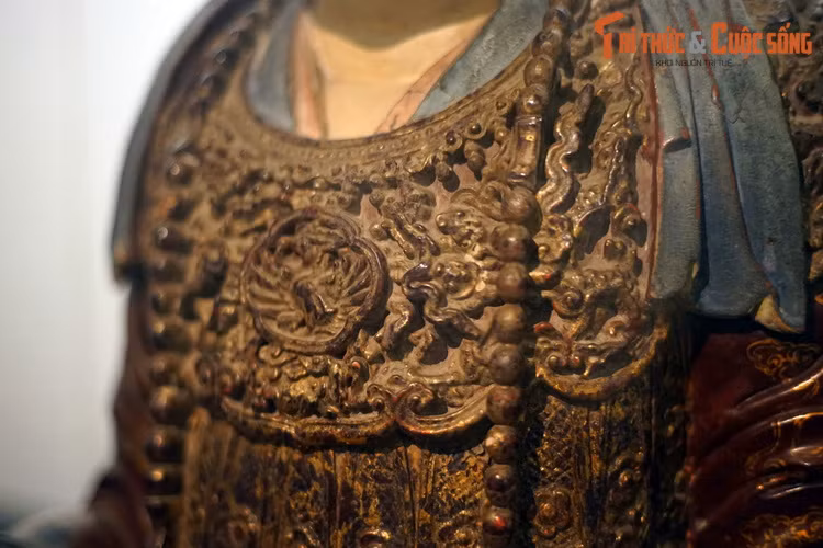 Trang phục của tượng là loại triều phục với ba lớp áo trong và một áo vân kiên khoác ngoài. Riêng tấm áo choàng vân kiên của tượng được đánh giá là đỉnh cao của nghệ thuật chạm khắc gỗ Việt Nam với mô típ lưỡng long triều phụng (đôi rồng chầu phượng) trước ngực.