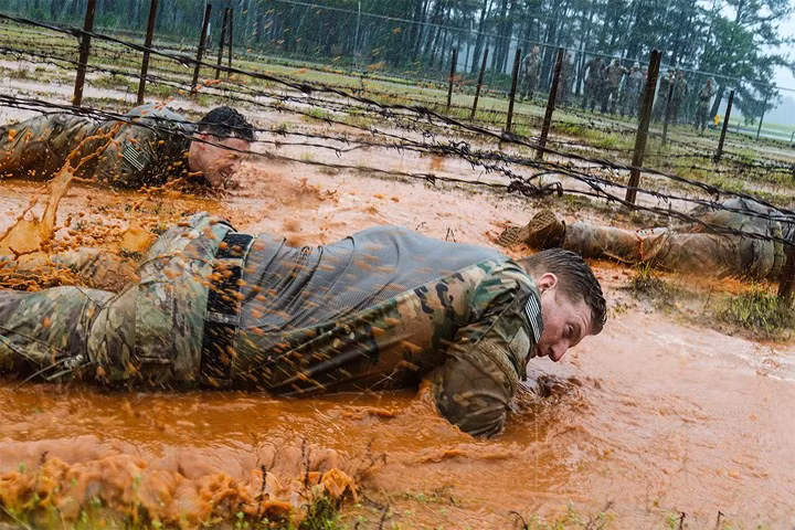 Một nhóm lính dù Mỹ tập bò qua hàng rào thép gai trong môi trường đầm lầy tại căn cứ không quân Mỹ ở Miami.
