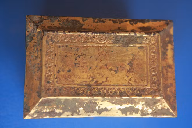 Theo quan sát, nắp hộp hình chữ nhật, ở bốn rìa cạnh của nắp hơi hõm xuống, nhìn tựa như rìa mái nhà, trên đỉnh nắp có băng trang trí hoa văn hoa cúc tròn 6 cánh.