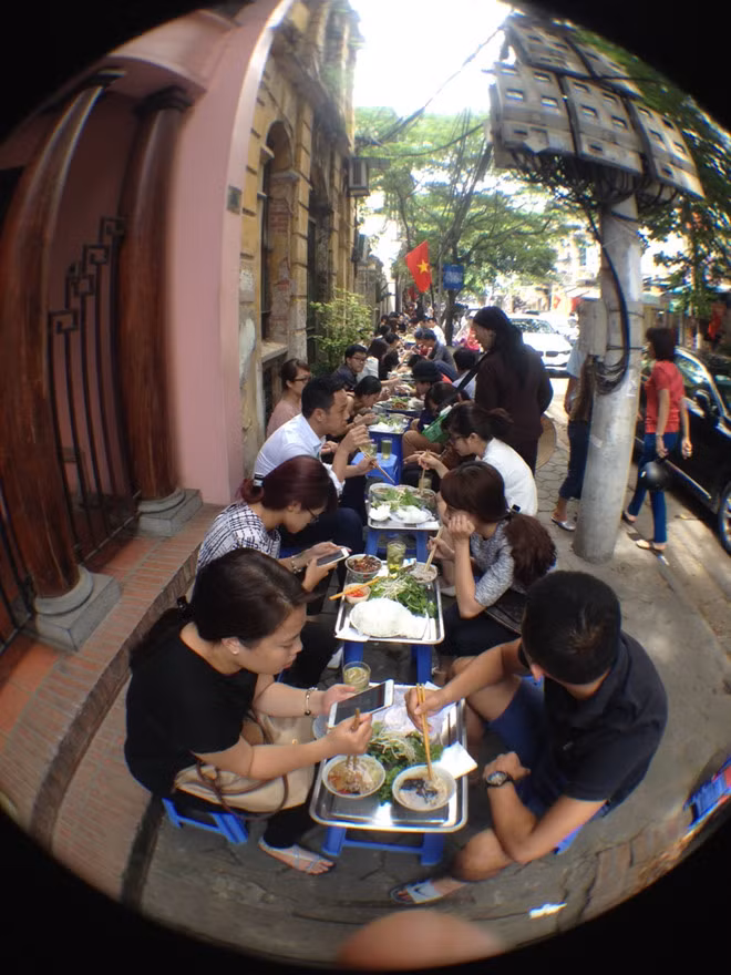 Khách ngồi ăn thành một dãy dài dằng dặc, thẳng tắp, tạo nên bức tranh ăn uống thú vị ở con phố này mỗi buổi trưa. Ảnh: Zing
