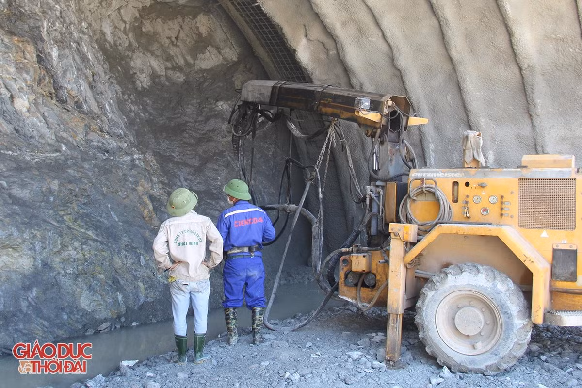Sau khi máy móc đào đất đá trong núi, công nhân sẽ dọn đất đá ra ngoài rồi ghim một lớp thép trên nóc hầm, đặt miếng đệm sắt, siết chặt đai ốc để làm kết cấu chống đỡ. Mái hầm thi công đến đâu sẽ được phun bê tông tươi gia cố chắc đến đó. (Ảnh: Giáo dục&amp;Thời đại).