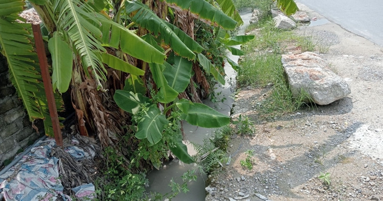 Lớp bùn thải, cùng với bã bê tông còn lắng đọng tạo thành một lớp dày dưới mương nước này.