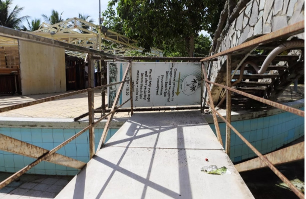 Bên trong công viên có nhiều điểm kinh doanh phục vụ khách quốc tế khi còn hoạt động. Một biển hiệu có tên nước ngoài được tận dùng để che các lối vào hồ bơi đang bỏ hoang sau khi doanh nghiệp dừng khai thác. (Ảnh: Vietnamnet).