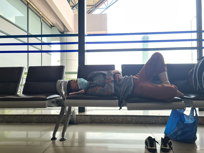 Một nữ hành khách trung tuổi tranh thủ chợp mắt trong thời gian chờ đợi chuyến bay.