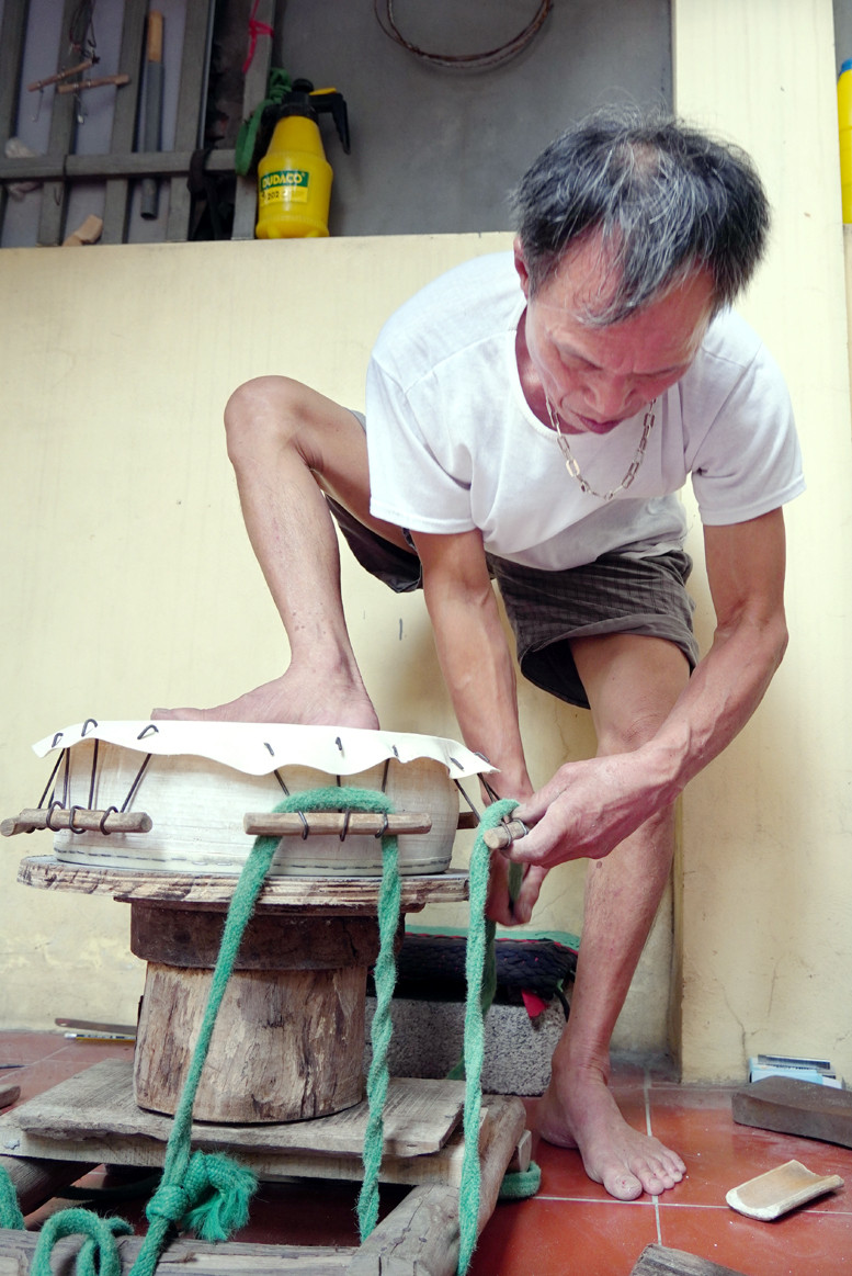 Ông Linh đang tròng kéo dây để néo da, giúp giữ căng bề mặt trống.