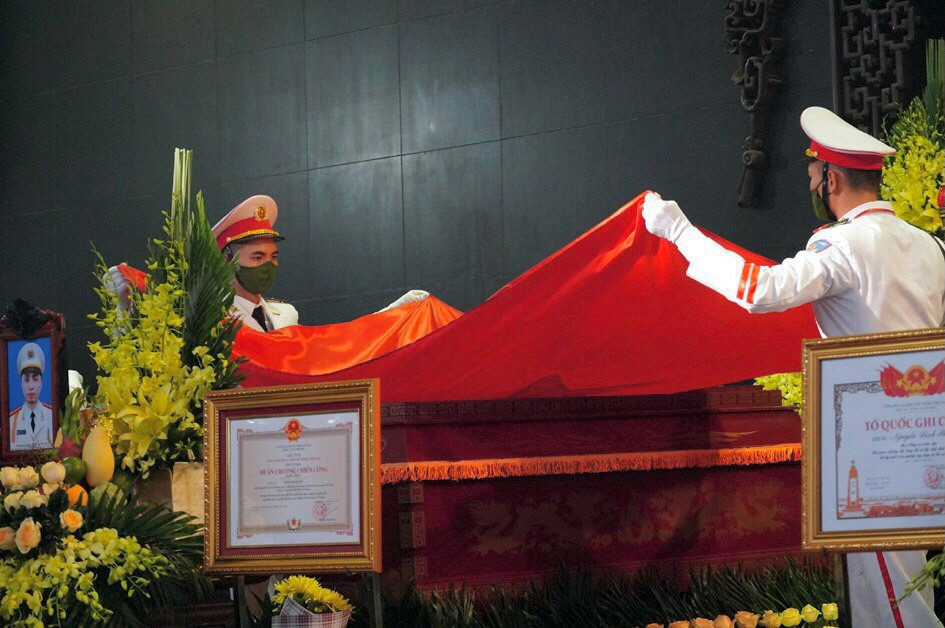 Nghi thức phủ cờ lên áo quan các liệt sĩ.