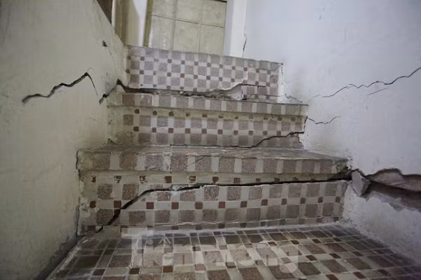 Khi bước lên những bậc cầu thang nhà ông Đa sẽ cảm nhận được hiện tượng nghiêng, cộng với các vết nứt to tiềm ẩn nguy cơ đổ sập bất kỳ lúc nào. Dẫu lo lắng nhưng hàng ngày, ông già 81 tuổi vẫn phải di chuyển qua những bậc thang nứt toác, lên tầng 2 để phơi đồ, cho mèo ăn. (Ảnh: Tiền Phong)