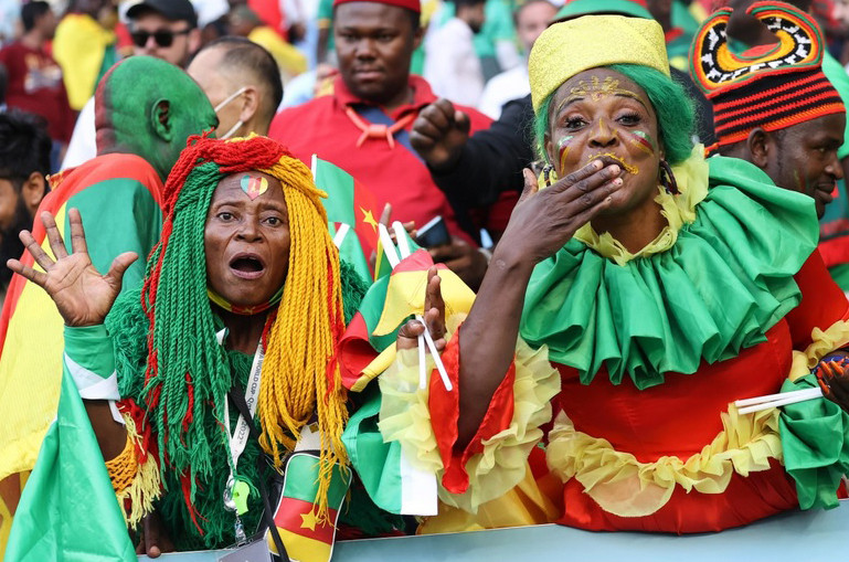 Cổ động viên đội tuyển Cameroon với tóc giả và trang phục mang mầu của quốc kỳ. 