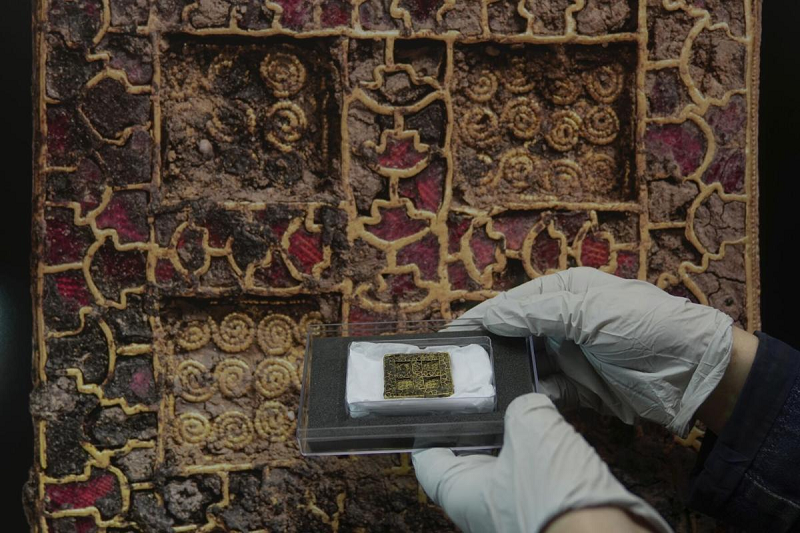 Kết quả chụp X quang lớp đất từ ngôi mộ hé lộ cây thánh giá trang trí tinh tế đúc bằng bạc với hình mặt người. Vật chất hữu cơ trong mộ chứa mảnh vụn của lông và da. Hai hũ gốm có thể đến từ khu vực ngày nay là Pháp hoặc Bỉ. Họ hy vọng phân tích phân tử sẽ cho phép xác định loại cặn trong hũ gốm.