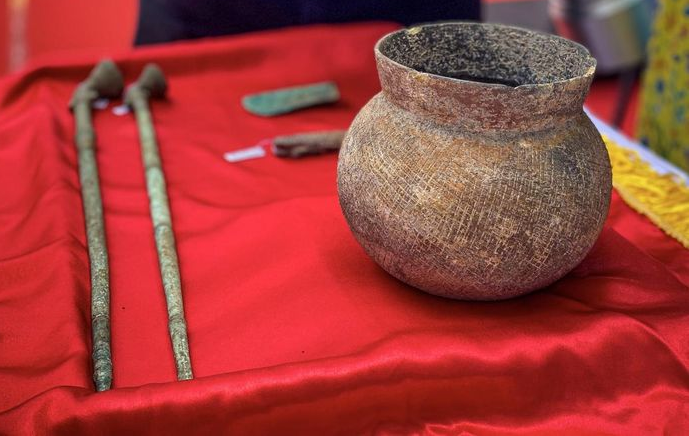 Nồi gốm được xác định niên đại thời Văn hóa Đông Sơn. Nồi miệng loe nhẹ, thân hình cầu, đáy tròn, gốm màu nâu vàng, thân trang trí văn chải.