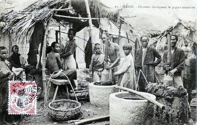 Nghề làm giấy: Trong ảnh chụp cảnh làng làm giấy ở Hà Nội, có thể là làng Bưởi. Những người thợ giã vỏ cây dó trong những chiếc cối đá lớn. Đây là nguyên liệu chính để làm giấy.