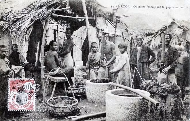 Nghề làm giấy: Trong ảnh chụp cảnh làng làm giấy ở Hà Nội, có thể là làng Bưởi. Những người thợ giã vỏ cây dó trong những chiếc cối đá lớn. Đây là nguyên liệu chính để làm giấy.