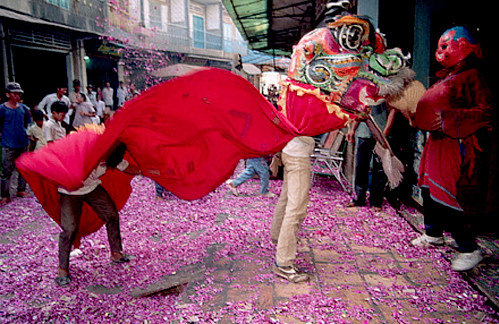 Người dân đứng xem múa lân sư rồng trong một con phố nhỏ.