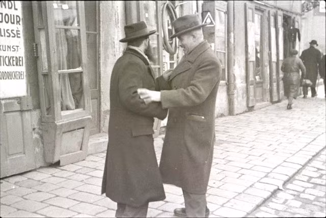 Hai người đàn ông tay bắt mặt mừng khi gặp nhau.