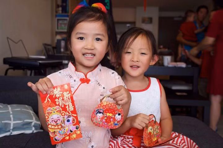 Hai bé gái thích thú khi nhận được tiền mừng tuổi của người lớn. Ảnh: ABC News.