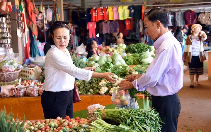 Trong ảnh là anh Vĩnh, cháu cụ Hồng - một gia đình người Việt tại làng Xiêng Vang, tỉnh Khăm Muộn, Lào đang đi chợ để chuẩn bị cho mâm cơm tất niên, xum họp gia đình.