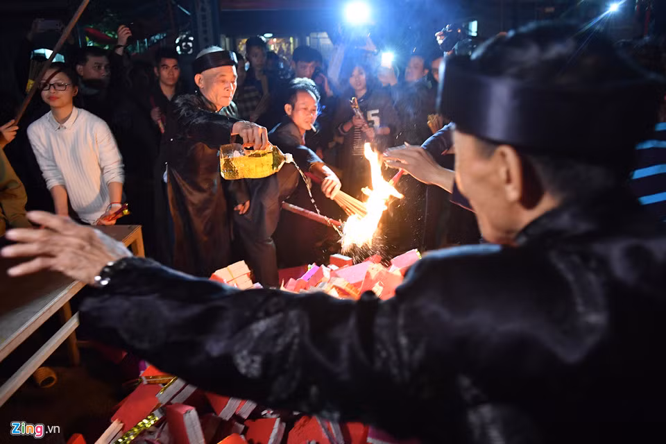 Để nhanh bén lửa, một bô lão khác trong làng dùng dầu đã chuẩn bị từ trước, đơm cho ngọn lửa.