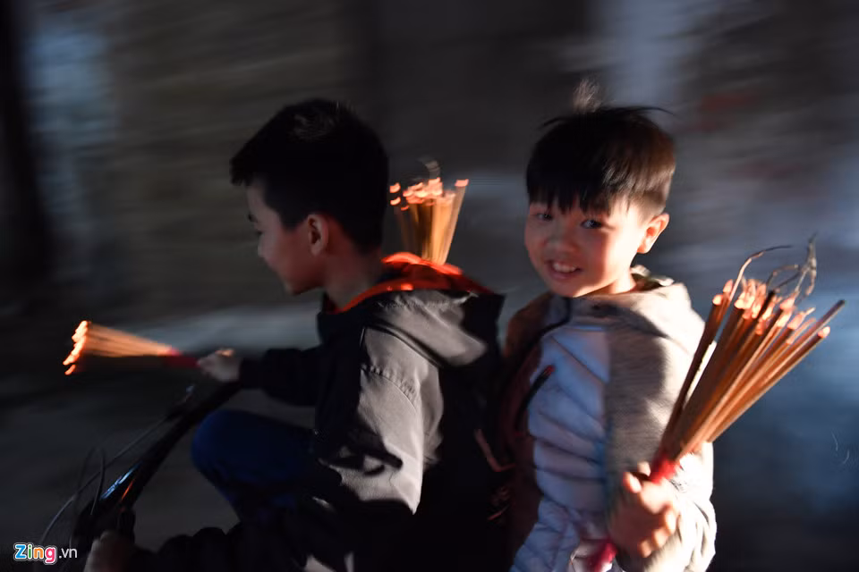 Cậu bé Dương Trọng Anh Quân (bên phải) cùng chú họ của mình vội vã trở về nhà sau khi xin được lửa tại sân đình. Cậu bé 10 tuổi đã bàn trước với chú mình chạy xe đạp cho nhanh mặc dù quãng đường về nhà chỉ khoảng hơn 200 m. Đây đã là lần thứ 2 Anh Quân được tự tay đi lấy đỏ tại đình làng.