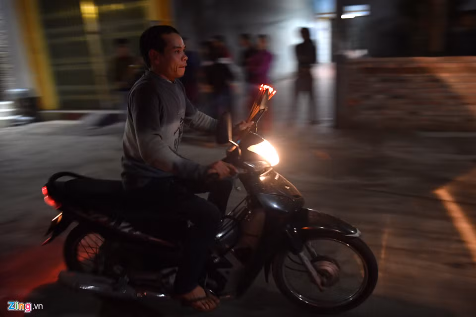 Trong lúc đó tại cổng đình làng, người dân vẫn tập nập xin lửa về nhà, nhiều người còn chạy xe máy cho nhanh.